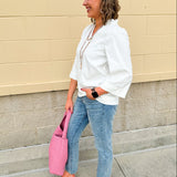 White blouse with ruffled V-neck and ¾ length wide sleeves, styled for a feminine, polished look.