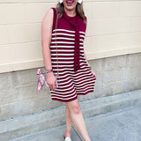 Garnet and white vertical striped sleeveless dress with round neckline, shoulder tie details, and knee-length silhouette.