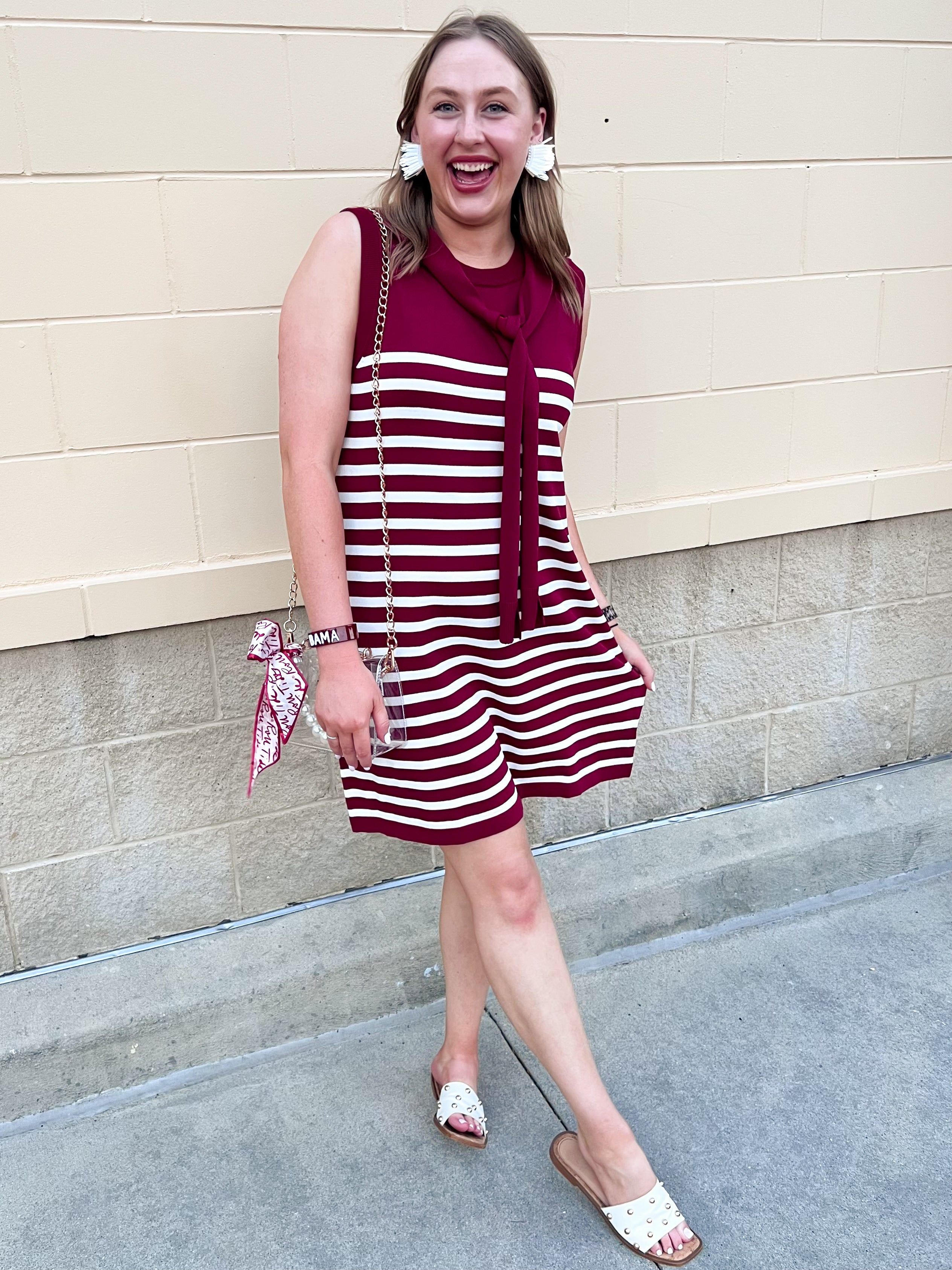 Garnet and white vertical striped sleeveless dress with round neckline, shoulder tie details, and knee-length silhouette.