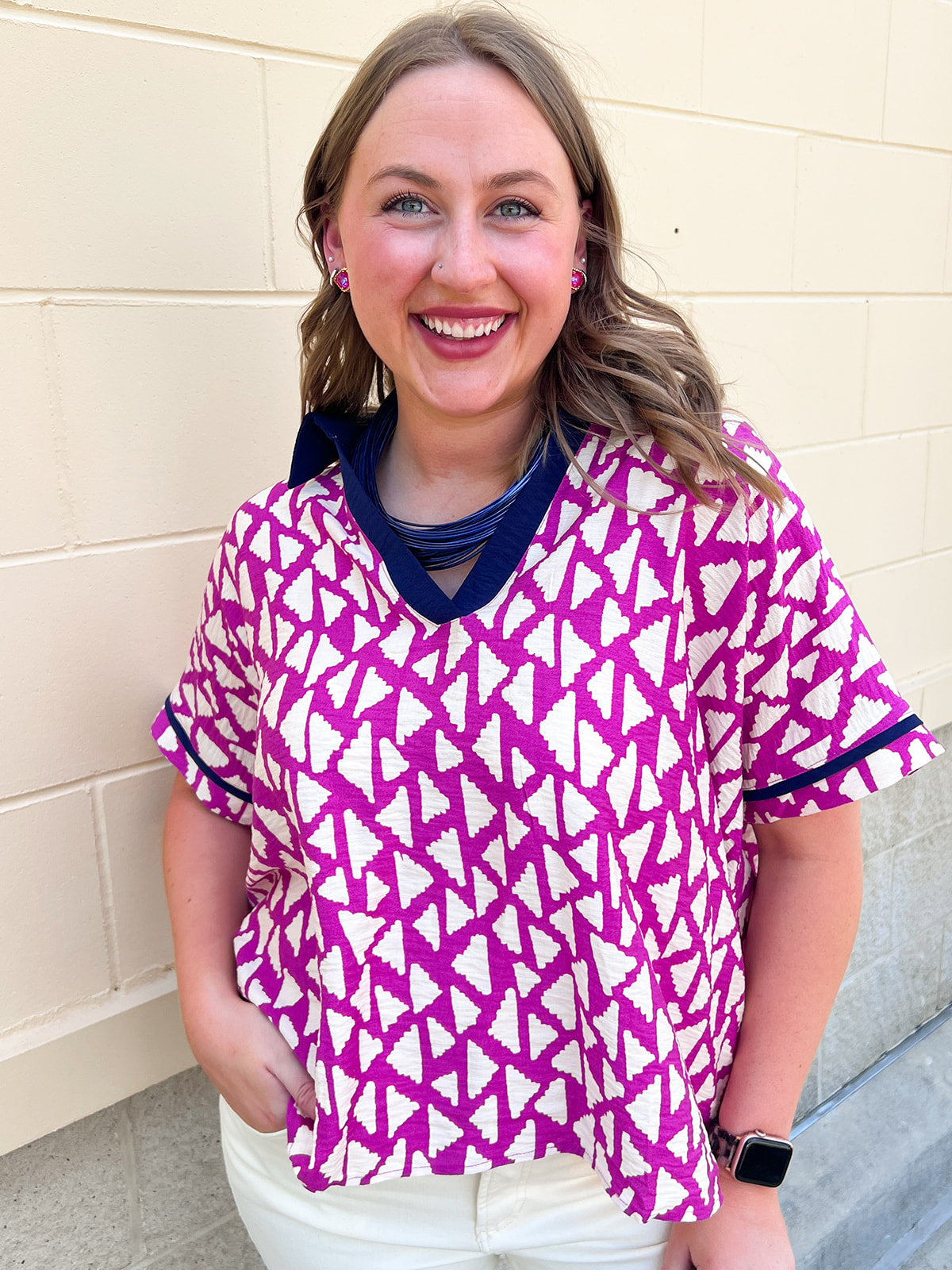 Hot pink and ivory abstract print women’s short sleeve top with navy contrast collar, V-neckline, and navy sleeve trim.