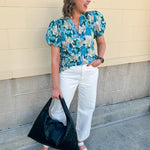 Blue floral blouse with pink accents, featuring a ruffle-trimmed split neckline and short puff sleeves