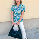 Blue floral blouse with pink accents, featuring a ruffle-trimmed split neckline and short puff sleeves