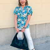 Blue floral blouse with pink accents, featuring a ruffle-trimmed split neckline and short puff sleeves