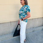Blue floral blouse with pink accents, featuring a ruffle-trimmed split neckline and short puff sleeves