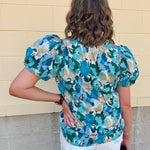 Blue floral blouse with pink accents, featuring a ruffle-trimmed split neckline and short puff sleeves