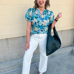 Blue floral blouse with pink accents, featuring a ruffle-trimmed split neckline and short puff sleeves