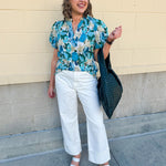 Blue floral blouse with pink accents, featuring a ruffle-trimmed split neckline and short puff sleeves