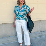 Blue floral blouse with pink accents, featuring a ruffle-trimmed split neckline and short puff sleeves
