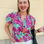 Vibrant raspberry floral blouse with ruffle-trimmed split neckline and short puff sleeves