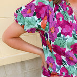 Vibrant raspberry floral blouse with ruffle-trimmed split neckline and short puff sleeves