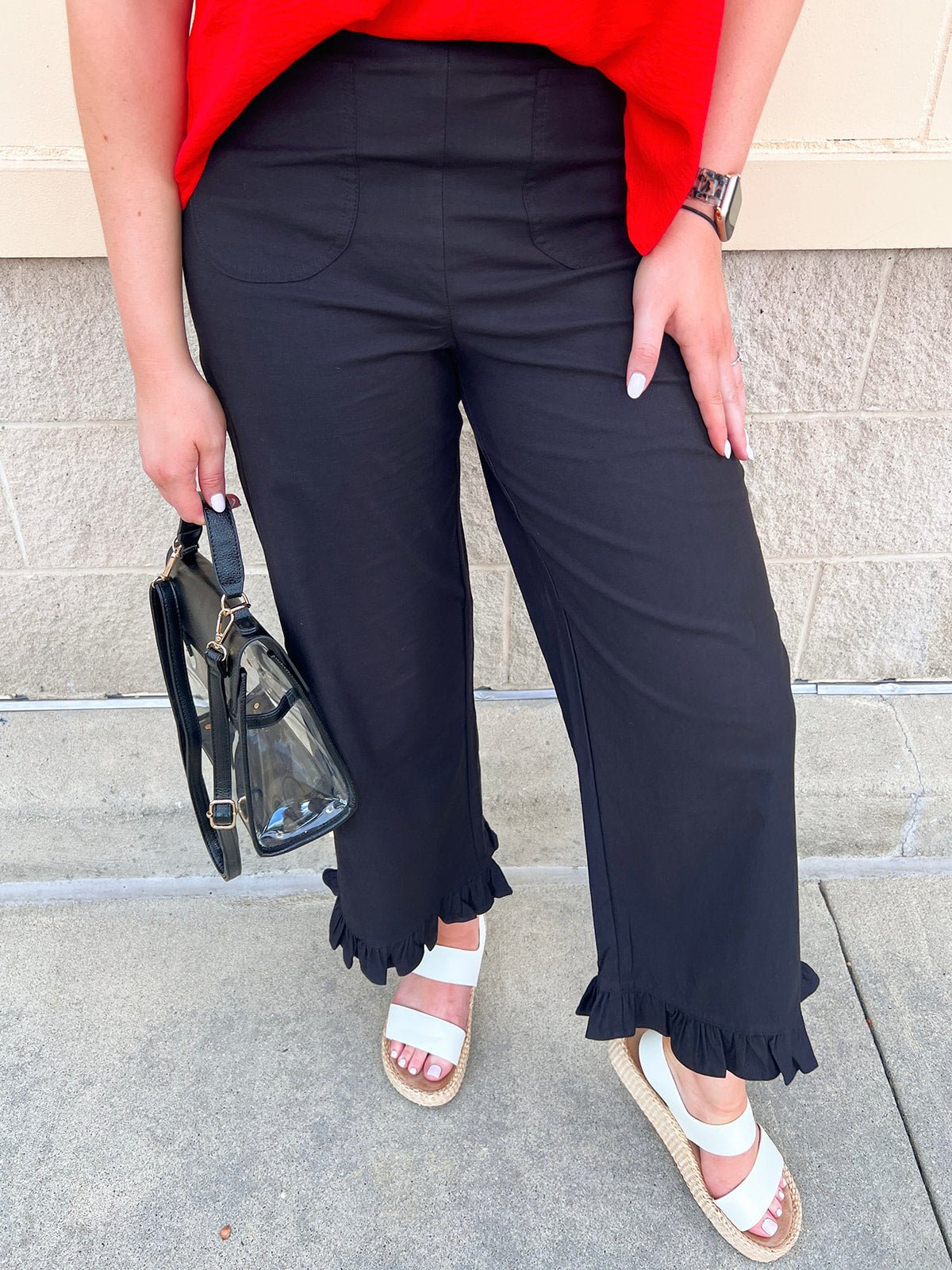 Black high-rise straight-leg pants with front patch pockets and ruffled hems.