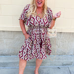 Garnet Aztec print knee-length dress with flutter sleeves, deep V-neckline, cinched waist, and flowy skirt.