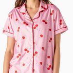 Pink pajama top with red cherry print, button-down front, collar, and red piping.