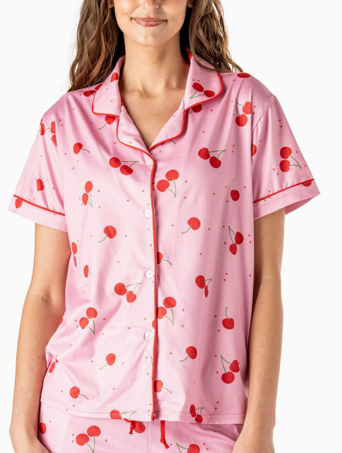 Pink pajama top with red cherry print, button-down front, collar, and red piping.