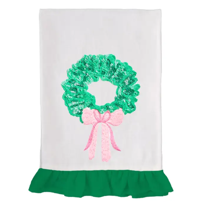 White tea towel with green sequin wreath, pink embroidered bow, and green ruffle trim — sparkling, festive, and perfectly giftable.