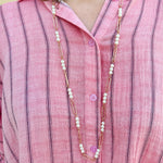 Oversized pink striped cotton gauze blouse with collar, button-down front, drop shoulders, and half sleeves.