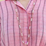 Oversized pink striped cotton gauze blouse with collar, button-down front, drop shoulders, and half sleeves.