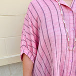 Oversized pink striped cotton gauze blouse with collar, button-down front, drop shoulders, and half sleeves.