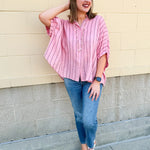 Oversized pink striped cotton gauze blouse with collar, button-down front, drop shoulders, and half sleeves.