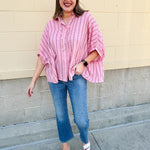 Oversized pink striped cotton gauze blouse with collar, button-down front, drop shoulders, and half sleeves.