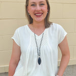  Neutral short sleeve top with smocking and pleated details, styled for a casual polished look