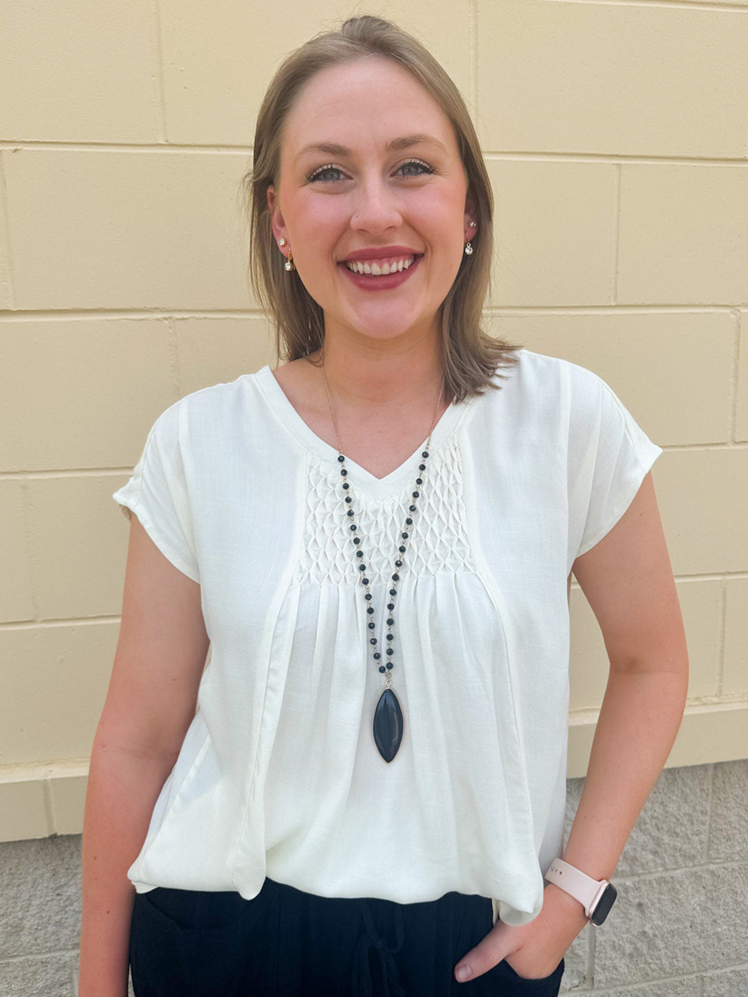  Neutral short sleeve top with smocking and pleated details, styled for a casual polished look