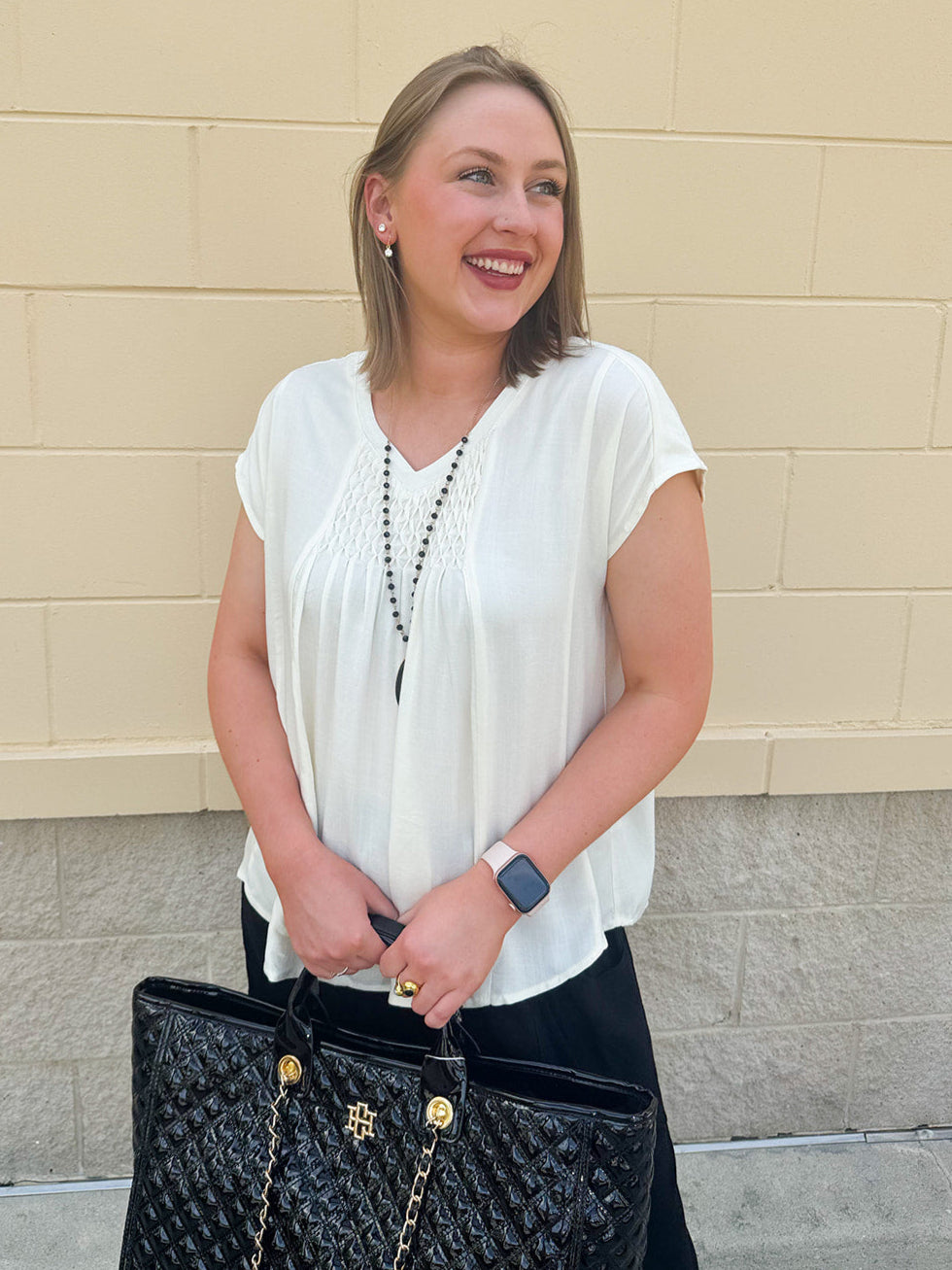  Neutral short sleeve top with smocking and pleated details, styled for a casual polished look