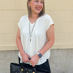  Neutral short sleeve top with smocking and pleated details, styled for a casual polished look