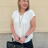  Neutral short sleeve top with smocking and pleated details, styled for a casual polished look