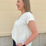  Neutral short sleeve top with smocking and pleated details, styled for a casual polished look