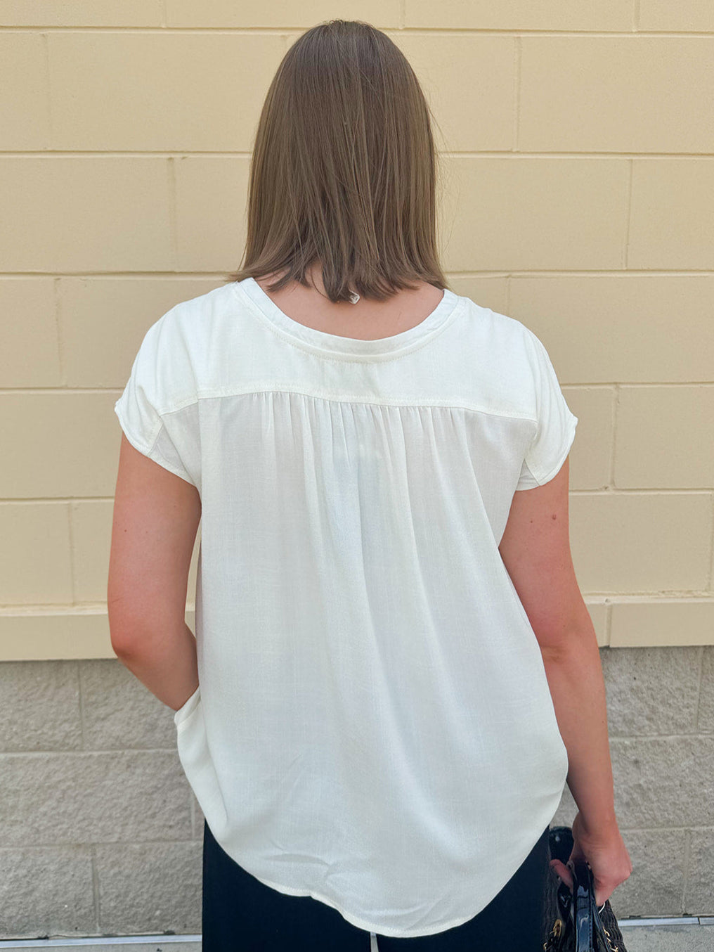  Neutral short sleeve top with smocking and pleated details, styled for a casual polished look