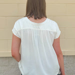  Neutral short sleeve top with smocking and pleated details, styled for a casual polished look