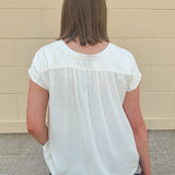  Neutral short sleeve top with smocking and pleated details, styled for a casual polished look