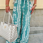 Lightweight printed wide-leg pants with a tropical pattern in dusty blue and cream tones, featuring a drawstring waist and pockets.