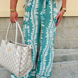 Lightweight printed wide-leg pants with a tropical pattern in dusty blue and cream tones, featuring a drawstring waist and pockets.