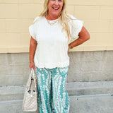 Lightweight printed wide-leg pants with a tropical pattern in dusty blue and cream tones, featuring a drawstring waist and pockets.