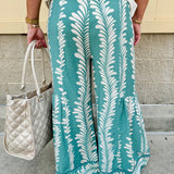 Lightweight printed wide-leg pants with a tropical pattern in dusty blue and cream tones, featuring a drawstring waist and pockets.