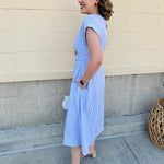 Model wearing the Skyline Views Striped Midi Dress with a classic striped pattern, cuffed short sleeves, and an elastic waistline – styled for a breezy, sun-soaked summer day by the coast or in the city