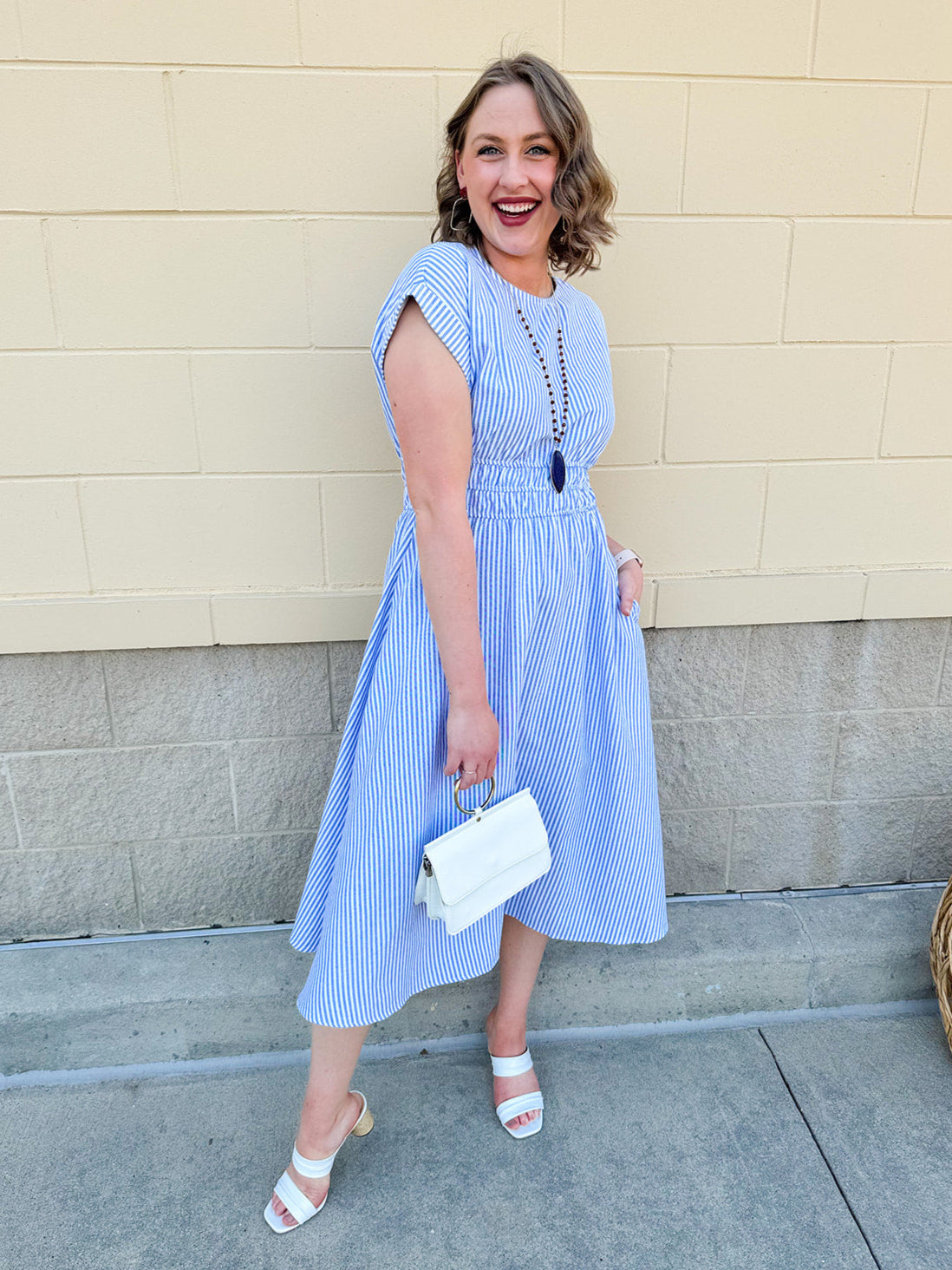 Model wearing the Skyline Views Striped Midi Dress with a classic striped pattern, cuffed short sleeves, and an elastic waistline – styled for a breezy, sun-soaked summer day by the coast or in the city