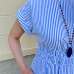 Model wearing the Skyline Views Striped Midi Dress with a classic striped pattern, cuffed short sleeves, and an elastic waistline – styled for a breezy, sun-soaked summer day by the coast or in the city