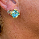 Bright gold-tone stud earrings with aquamarine square-cut crystals and a metal beaded halo from Sorrelli’s Aquamarine Collection.