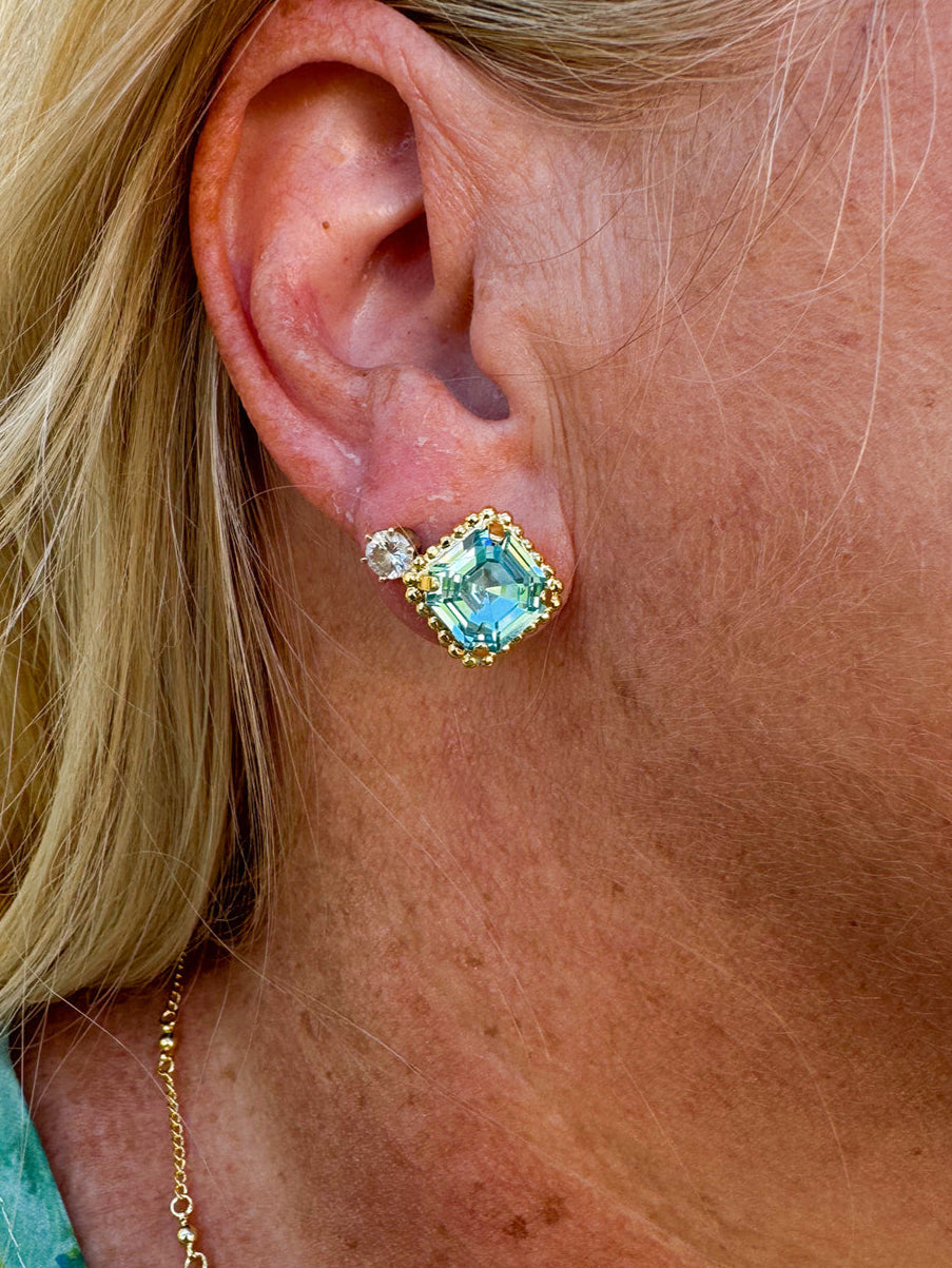 Bright gold-tone stud earrings with aquamarine square-cut crystals and a metal beaded halo from Sorrelli’s Aquamarine Collection.