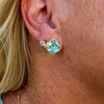 Bright gold-tone stud earrings with aquamarine square-cut crystals and a metal beaded halo from Sorrelli’s Aquamarine Collection.