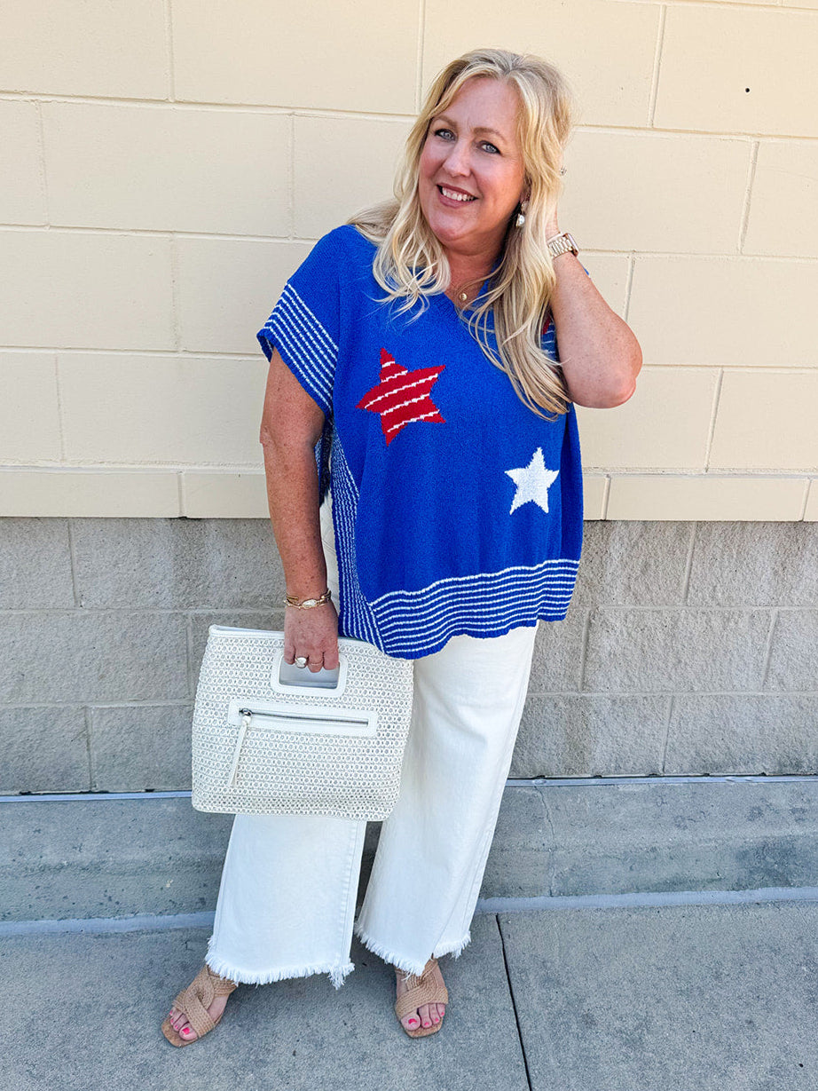 Oversized blue poncho sweater with three Americana stars on front and white striped details, styled for patriotic summer events.
