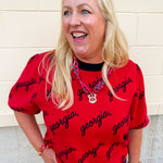 Women's bulldog red puff sleeve knit sweater featuring scattered black cursive georgia lettering and a classic crew neckline.