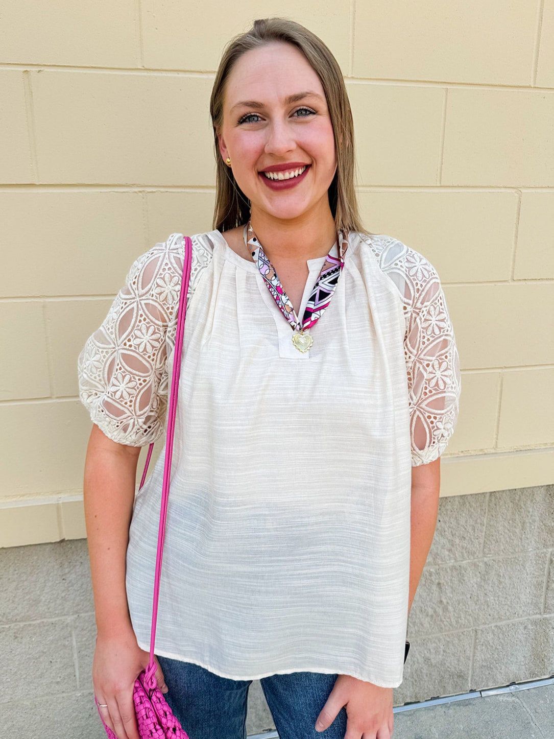 Cream-colored split neck top with lace sleeves, styled for lightweight comfort and feminine charm.
