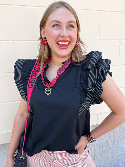 Black woven top with split neckline, short ruffle sleeves, and stitch detailing.