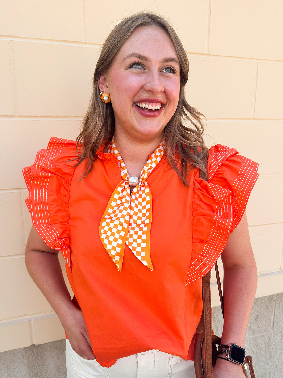 Orange woven top with split neckline, short ruffle sleeves, and stitch detailing.
