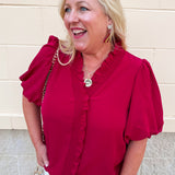 Bright garnet short sleeve top with smocked neckline, bubble sleeves, and ruffled hem detail.