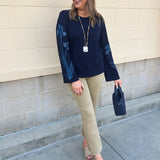 Navy blue sweatshirt with oversized light blue and white embroidered flowers covering both sleeves